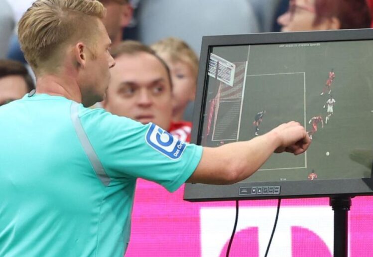 Wasit meninjau tayangan VAR dalam pertandingan sepak bola Indonesia untuk menentukan keputusan penting di lapangan