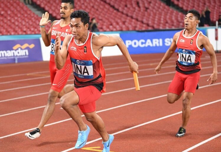 Atlet berlari sprint di lintasan atletik stadion dengan teknik start cepat dan fokus pada kecepatan maksimal