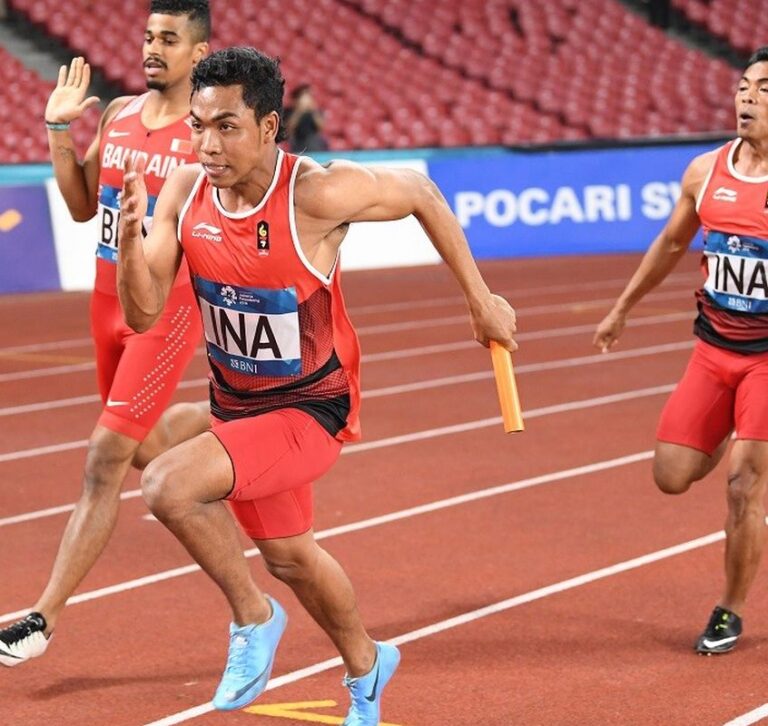 Atlet berlari sprint di lintasan atletik stadion dengan teknik start cepat dan fokus pada kecepatan maksimal
