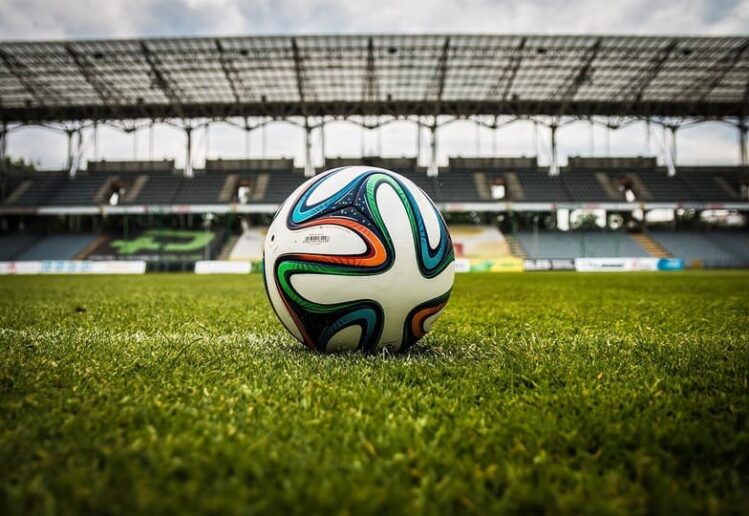 Pemain sepak bola modern sedang bertanding dengan dukungan teknologi analisis data dan VAR di stadion
