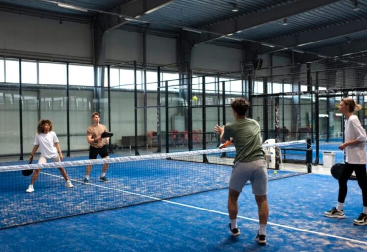 Pemain pickleball sedang bertanding di lapangan olahraga modern